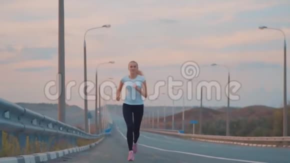 积极的生活方式和保健一个穿着白色T恤和轻便运动鞋的运动女孩在外面的一条空跑道上奔跑视频的预览图