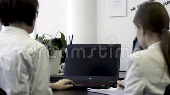 在办公室工作的两个女孩的后视图看看带有空白可编辑绿色屏幕的笔记本电脑商业妇女的概念视频的预览图