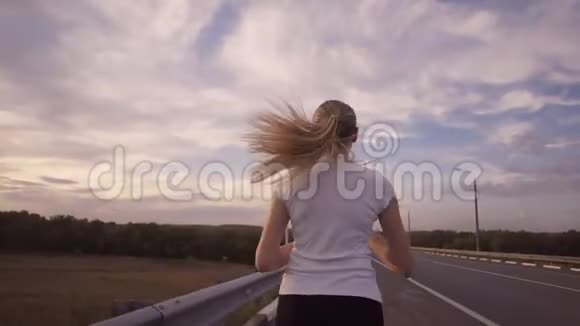 积极的生活方式和保健一个穿着白色t恤留着长发的运动女孩跑在一条几乎空空如也的跑道上视频的预览图