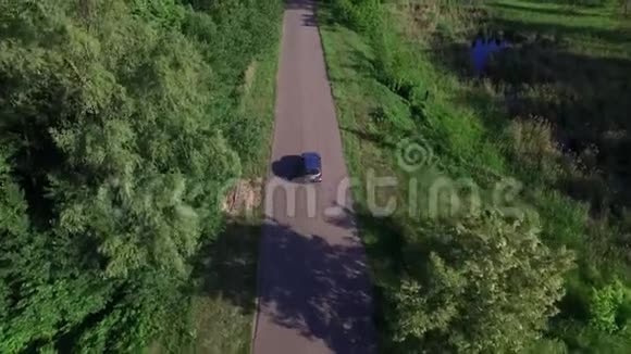 在穿过绿色森林的乡间道路上驾驶的无人观景车视频的预览图