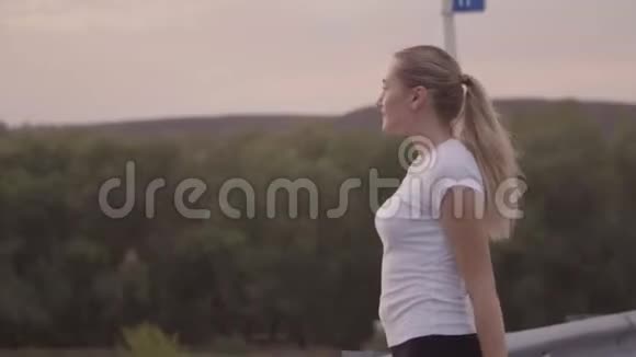 积极休息景观优美一个穿着白色T恤和明亮运动鞋的女孩在外面的一条空跑道上奔跑视频的预览图