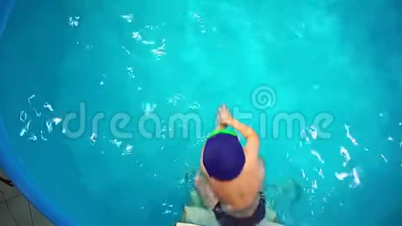 一个小男孩在游泳池里学游泳俯视他跳进水里视频的预览图