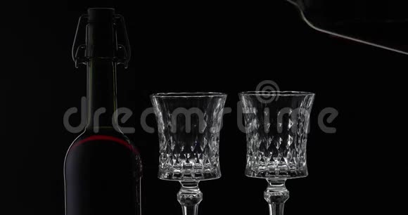 玫瑰酒红葡萄酒倒入两个酒杯在黑色背景上剪影视频的预览图