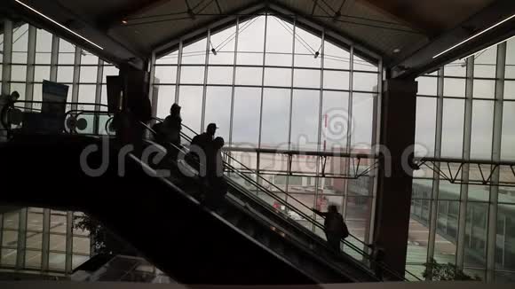 机场内的移动自动扶梯站在自动扶梯上的人们剪影视频的预览图