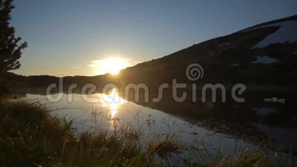 一个风景如画的湖在秋天的一个绚丽的日落中有一个丘陵的河岸视频的预览图