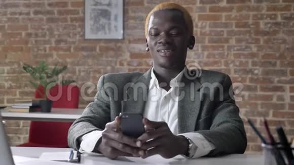 年轻的非洲时髦商人金发打电话坐在办公室耳朵穿孔的男人视频的预览图