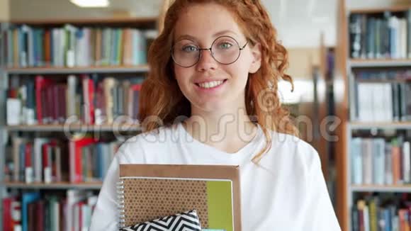 大学图书馆里拿着书的学生美女微笑的画像视频的预览图