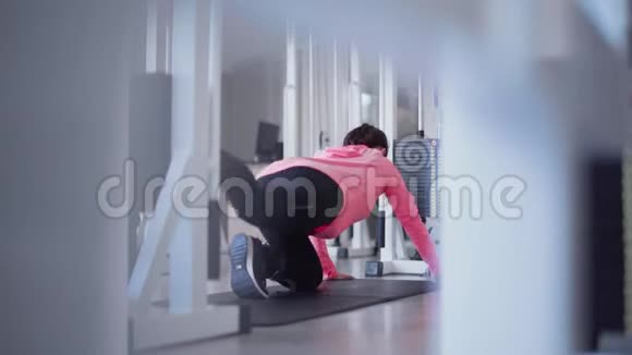 女性正在做力量性锻炼腿在健身房站在膝盖上健身房里的人视频的预览图