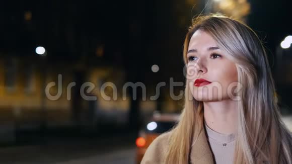 漂亮的女人在夜城的街道上等出租车女孩叫出租车在线服务出租车订单移动应用视频的预览图