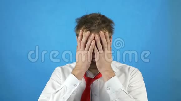 一个年轻的白种人穿着白色的衬衫打着领带在酒精波顿嗜睡和蓝色背景下擦脸视频的预览图