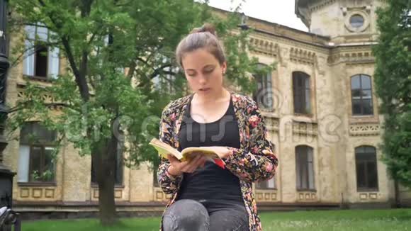 年轻的美女坐着看书问候某人然后离开停在大学背景附近视频的预览图