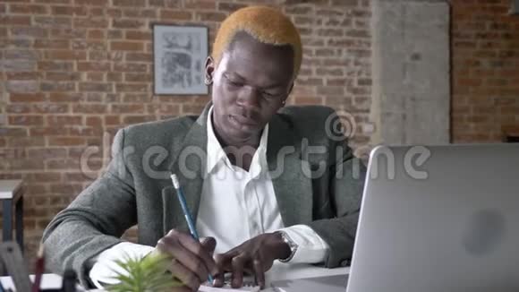 年轻自信的非裔美国商人在现代办公室里写笔记和打字工作繁忙视频的预览图