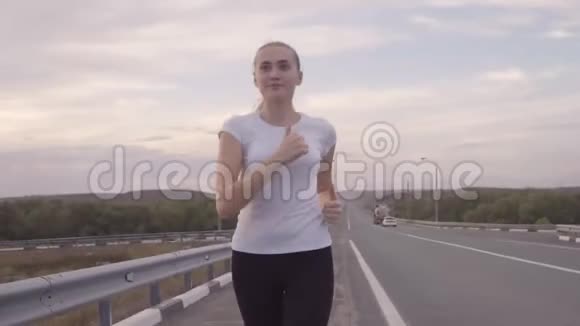 积极休息景观优美一个穿着白色T恤和明亮运动鞋的女孩在外面的一条空跑道上奔跑视频的预览图