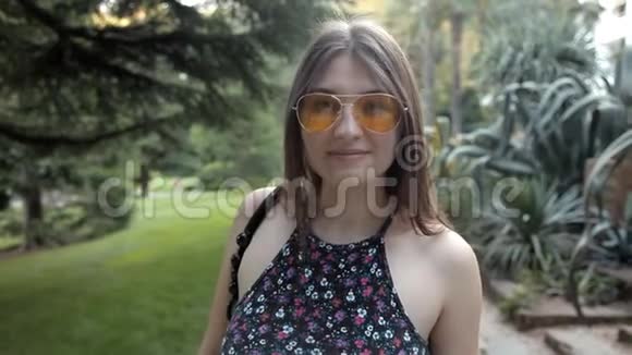 一个年轻的女孩在夏天的绿色公园里散步开始欢快地跳舞视频的预览图
