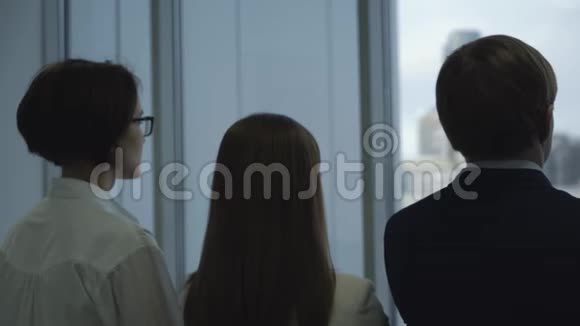 三个商务人士在办公室的窗户附近近距离接触自己的下巴后景视频的预览图