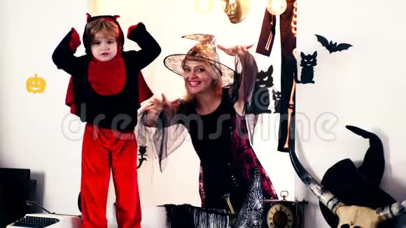 一个穿着女巫套装的女人和一个穿着龙服的小男孩在万圣节假期里吓着每个人幸福家庭视频的预览图