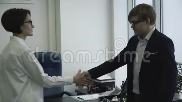 微笑的商人在办公室里握手商务会议视频的预览图