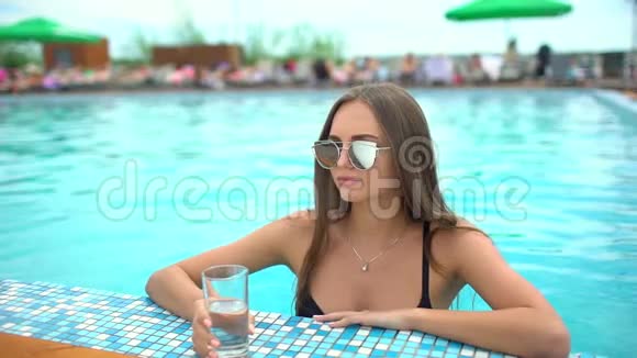 夏天美丽的年轻女子比基尼女孩在热带游泳池放松女人喝干净的水这就是视频的预览图