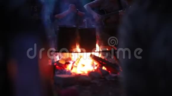 人们用篝火在水桶里加热水一个在后台弹吉他的男人视频的预览图