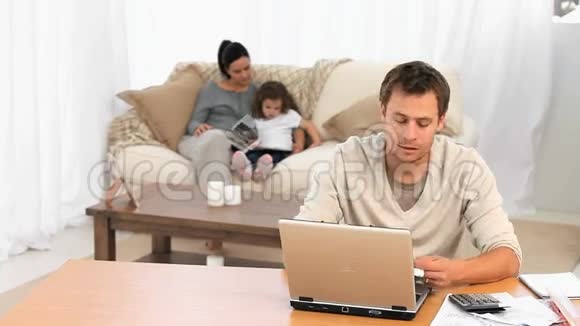 担心的男人一边给女儿读书一边计算账单视频的预览图