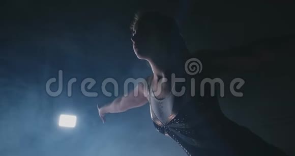 在烟雾中缓慢运动一个女运动员站着她的手臂举起后表演练习欢迎手势视频的预览图