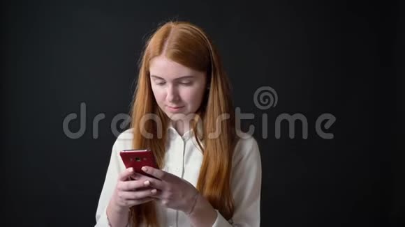 一位年轻迷人的女人长着姜发打着电话对着镜头微笑在黑色的背景下被隔离视频的预览图