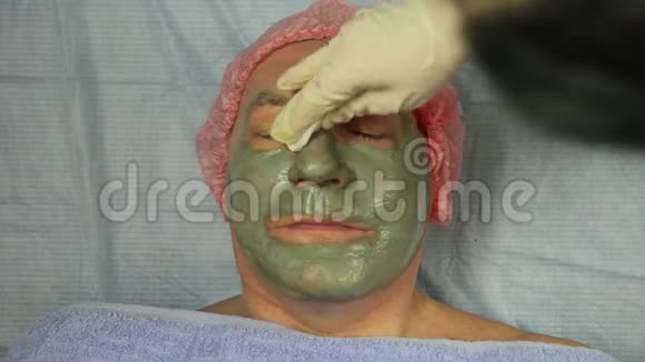 美容师的手从一个人身上取下一个泥面具视频的预览图