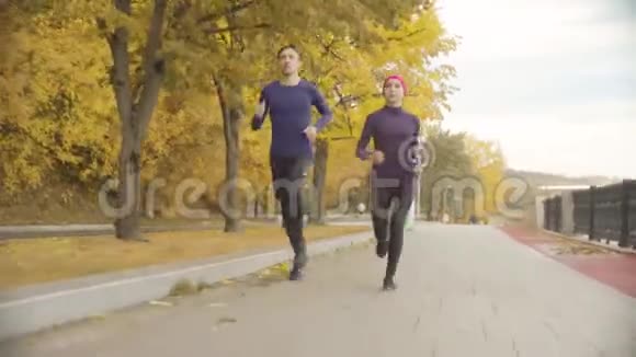年轻的女运动员和运动员在路上奔跑视频的预览图