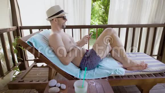 一个戴眼镜的成年人喜欢白天用手机听音乐而这个人躺在一个视频的预览图