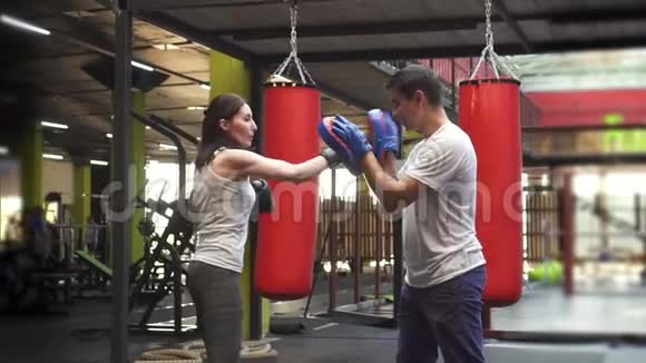 在健身房和教练一起做拳击的女人慢节奏视频的预览图