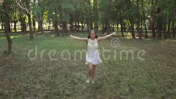 日落时分穿着白色短裙长发的快乐女孩穿过公园视频的预览图