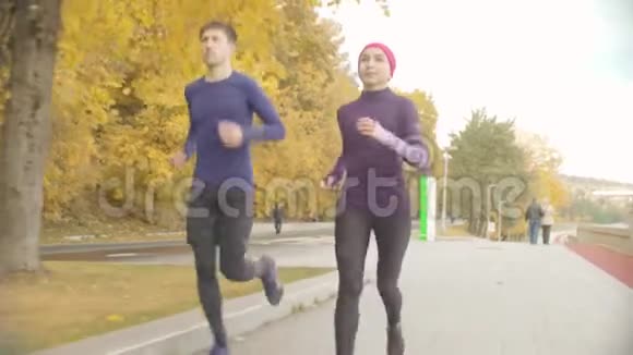 年轻的女运动员和运动员在路上奔跑视频的预览图