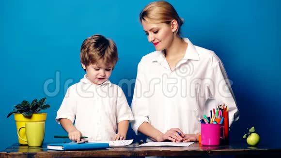 年轻的女人带着一个用彩色铅笔画的小男孩在蓝色的背景上进行情感交流妈妈和儿子视频的预览图