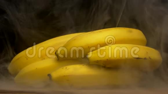 黑色背景下的一串新鲜香蕉来自汗水和凉爽烟雾特写4K视频的预览图