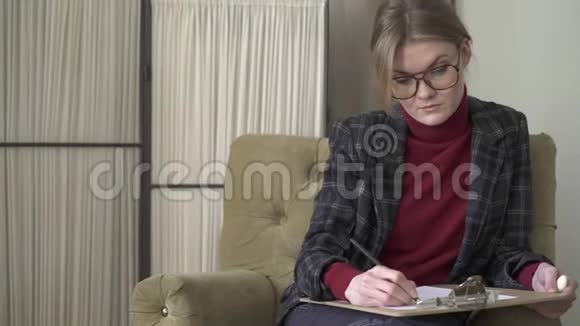 一个戴眼镜的年轻女子在写字板上写字视频的预览图