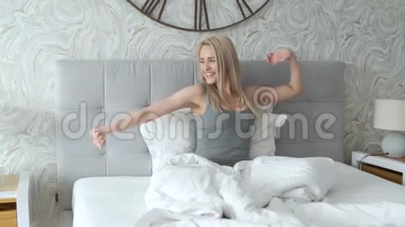 快乐的年轻女子在床上享受阳光明媚的早晨视频的预览图