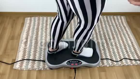 穿条纹紧身裤的女人在振动模拟器上进行体育锻炼运动减肥体能的概念视频的预览图