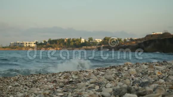 海浪拍打着一片空旷的海滩在城市景观的背景下产生了海洋泡沫塞浦路斯海岸夏日视频的预览图