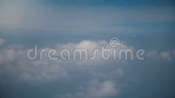 从飞机窗口拍摄的史诗背景空中镜头在田园般宁静的蓝色阳光天空中在令人惊叹的白云之上飞行视频的预览图