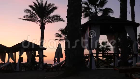 美丽的家庭漫步在塞浦路斯海滩上的休闲区美丽的日落时有棕榈树和帐篷视频的预览图