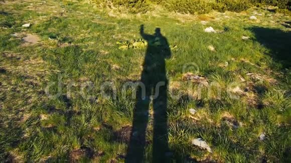 一个高大的人用手缓慢地举起绿色草坪的影子视频的预览图