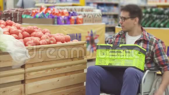 在超市里买轮椅的残疾人选择西红柿然后把它们放进一个包裹里视频的预览图