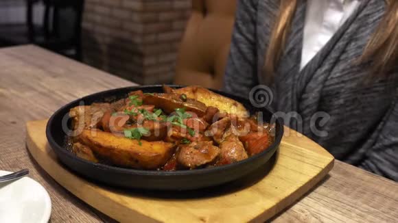 女人在咖啡馆里吃煎土豆在木板上烤盘手特写视频的预览图