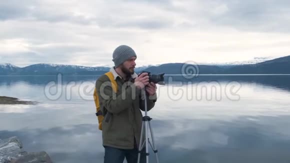专业摄影师男带单反背包拍摄山谷风景视频的预览图