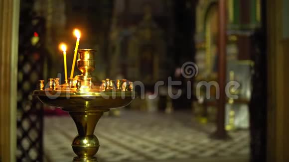 教堂里两支蜡烛放在教堂背景模糊的烛台上视频的预览图