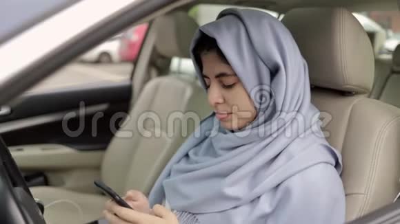 漂亮的年轻女人戴着头巾在车里上网放大镜头视频的预览图