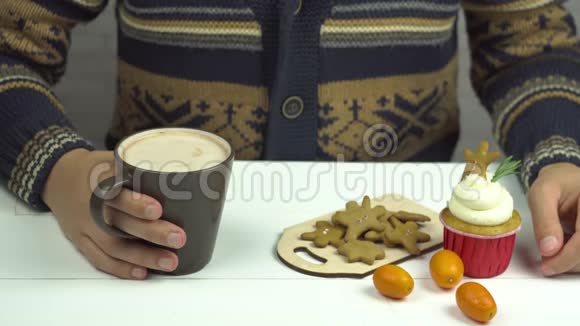 男人手把姜饼放在可可里桌上的纸杯蛋糕和金橘视频的预览图