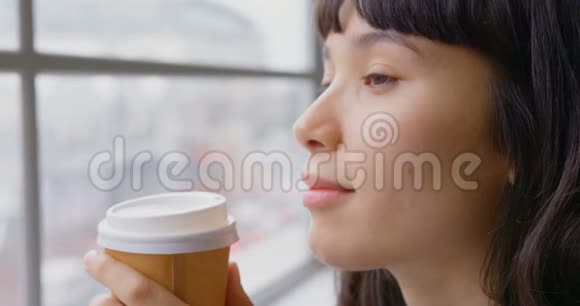 女商人一边喝咖啡一边坐在靠近窗户的现代化办公室视频的预览图