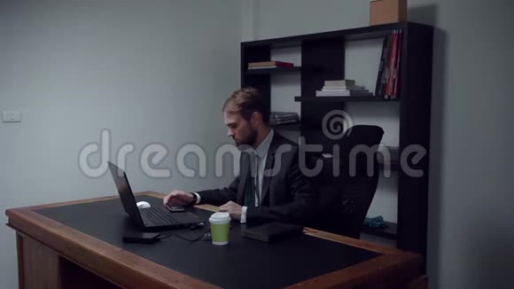 大胡子商人坐在办公室男工人在工作时在电话里看电影动作慢视频的预览图