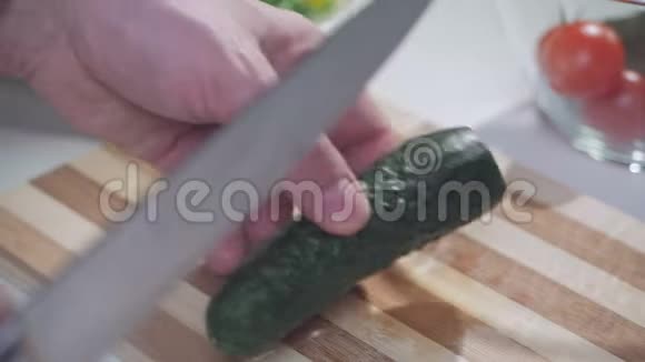 一个人用一把刀在一块分割的木板上切绿色的茄子用来做蔬菜沙拉视频的预览图